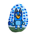 Hand painted blue pup standing in the grass on a natural stone rock