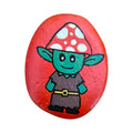 Hand painted green forest friend in a red spotted toadstool hat on a red rock