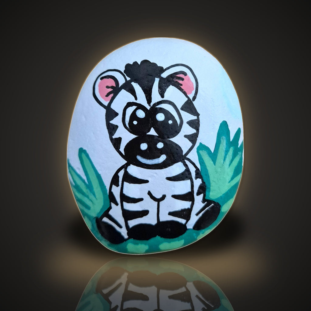 Ziggy Stripes, a hand painted baby zebra rock sitting in green grass, on a black and gold background