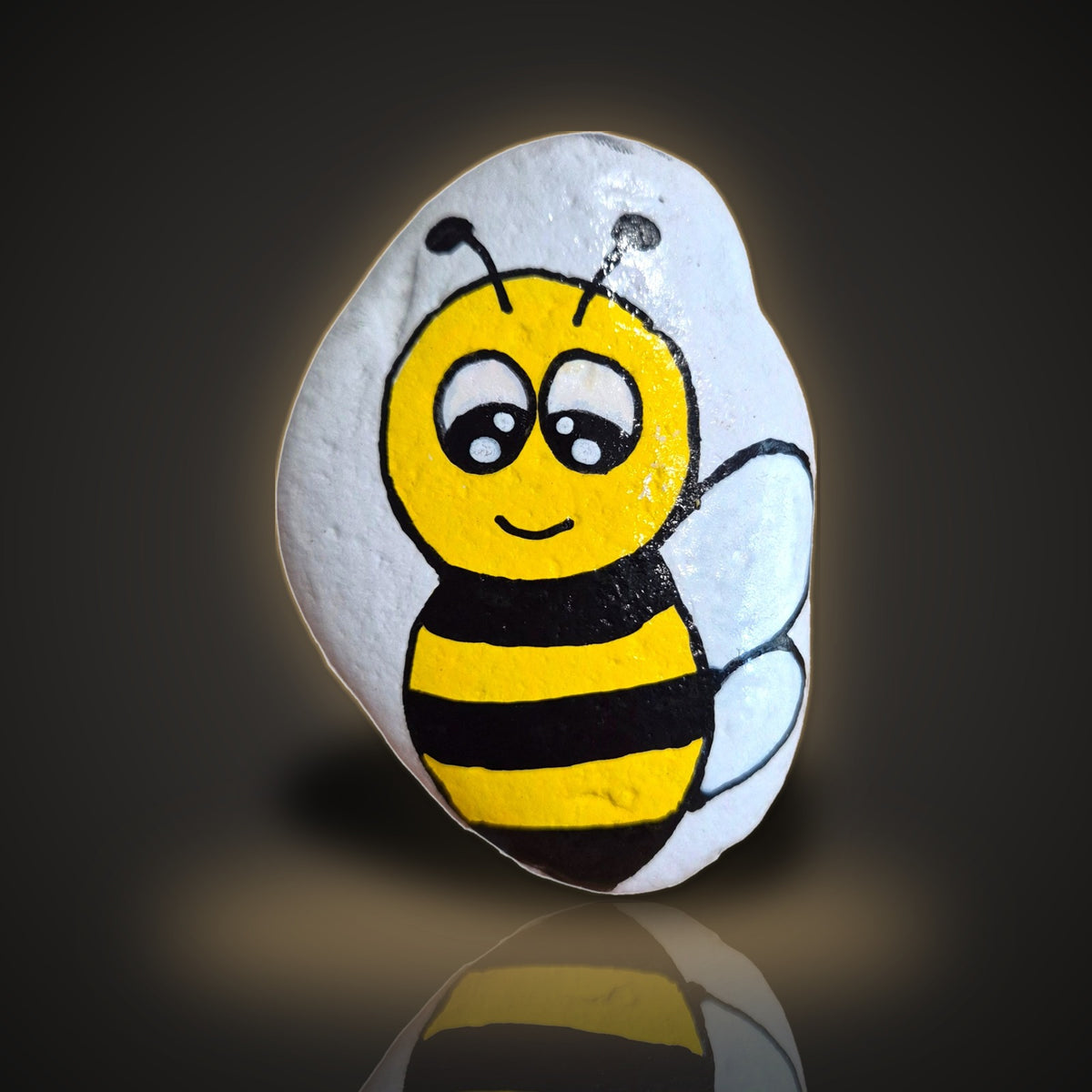 Bea Happy, a hand painted black and yellow bumble bee rock, on a black and gold background