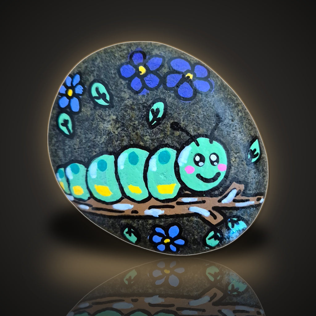 Stick Around Sid, a hand painted caterpillar on a stick rock, on a black and gold background