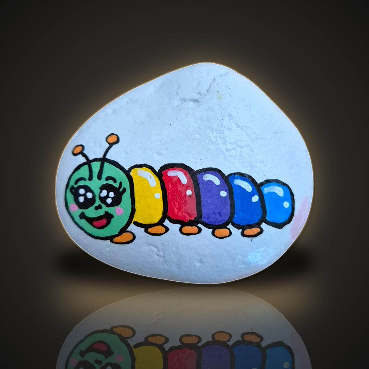 Rainbow Wiggles, a hand painted colourful rainbow caterpillar rock, on a black and gold background