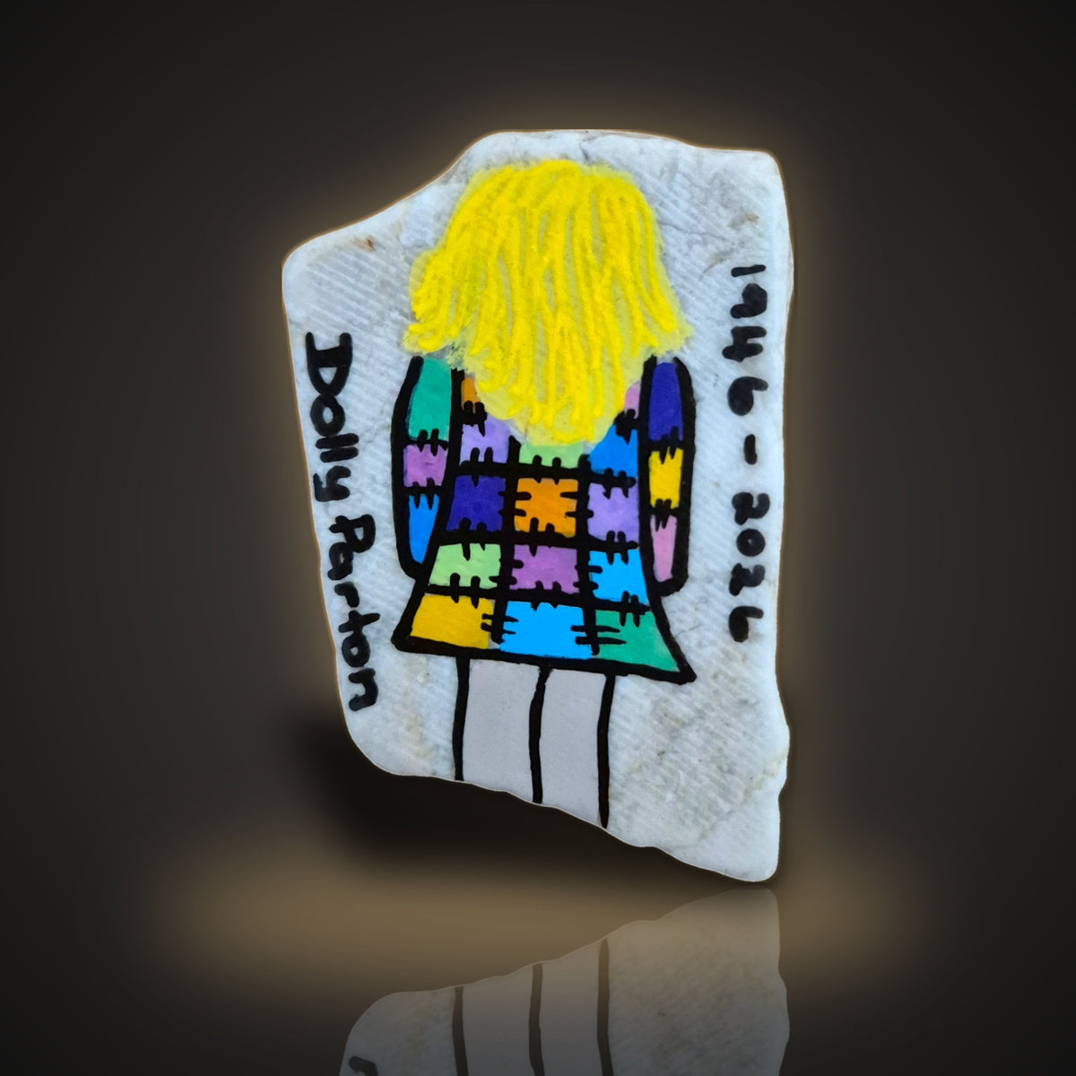 Patchwork Queen, a hand painted patchwork coat tribute rock with the years 1946-2026, on a black and gold background