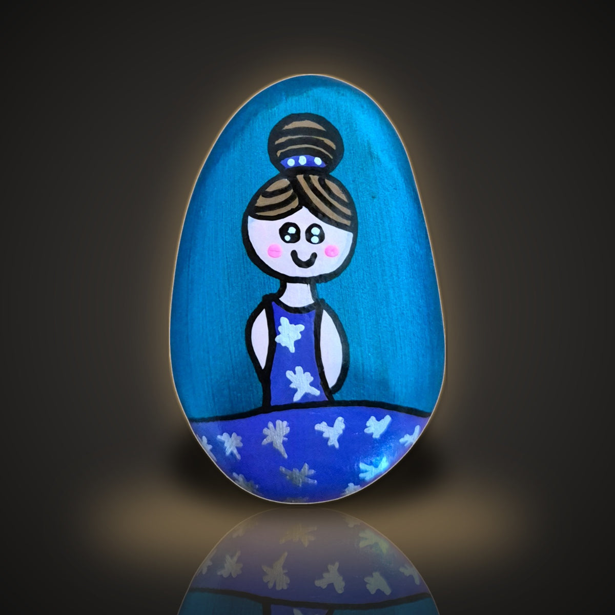 Penny Pirouette, a hand painted ballerina rock in a blue and purple tutu, on a black and gold background