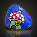 Shroomsville, a hand painted red mushroom house rock on a purple background, on a black and gold backdrop