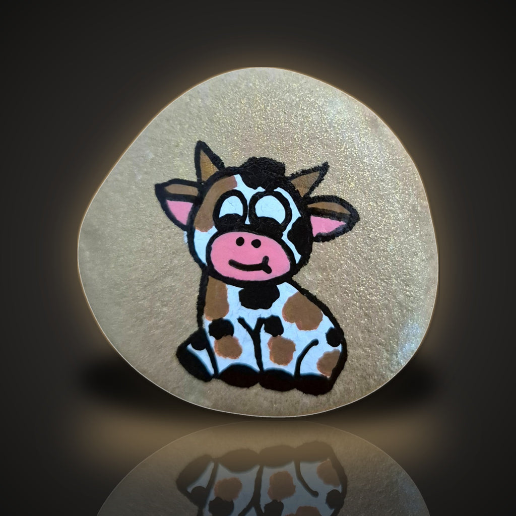 Glitter Moo, a hand painted cow rock on a sparkling glitter background, on a black and gold backdrop