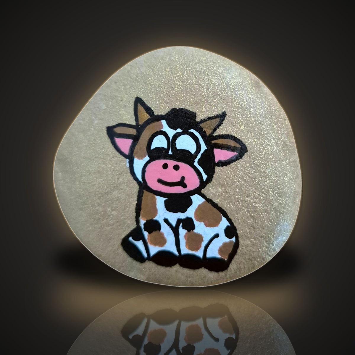 Glitter Moo, a hand painted cow rock on a sparkling glitter background, on a black and gold backdrop