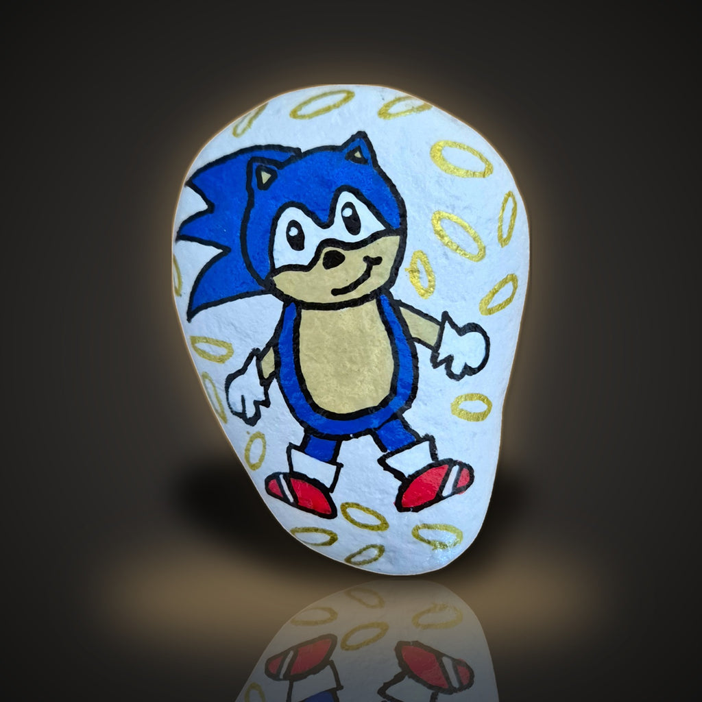 Ring Dash, a hand painted speedy blue hedgehog rock surrounded by gold rings, on a black and gold background